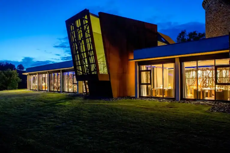 Extension contemporaine du Château du Couffour avec grandes fenêtres illuminées la nuit.