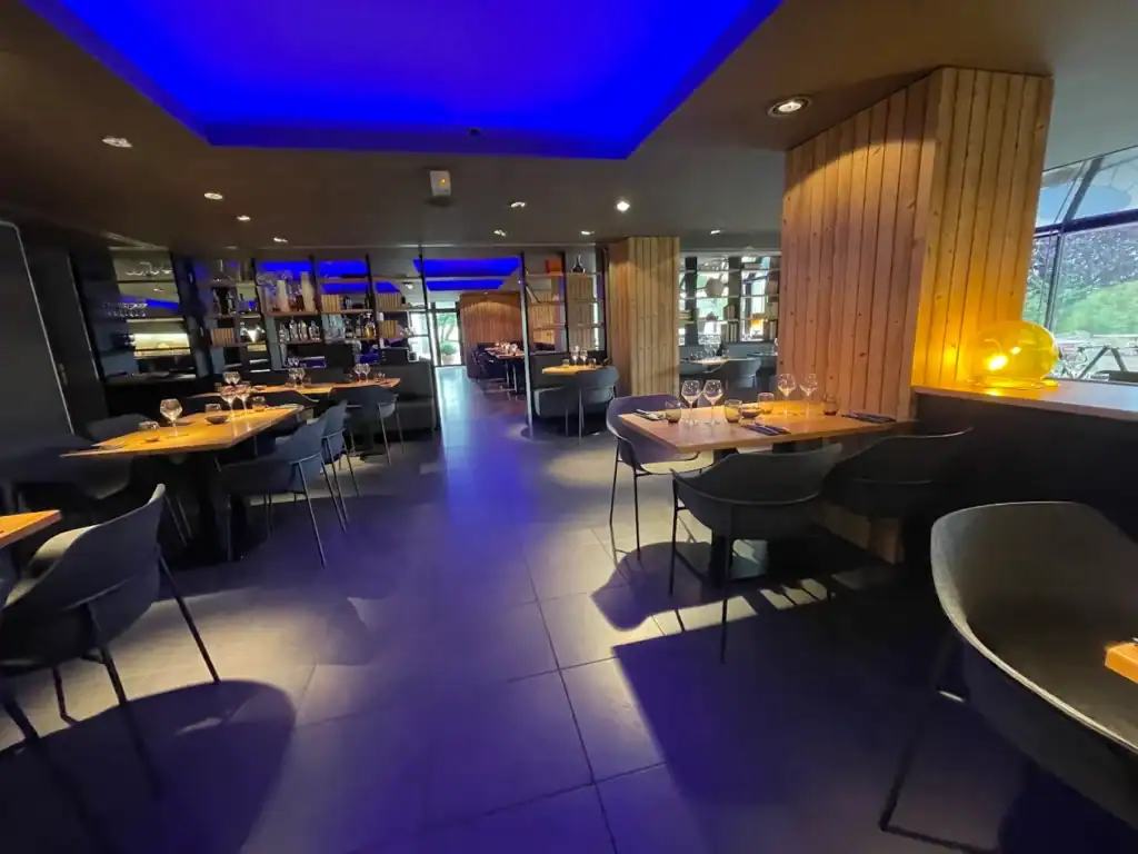 Salle intérieure du restaurant avec éclairage d'ambiance bleu et mobilier contemporain.