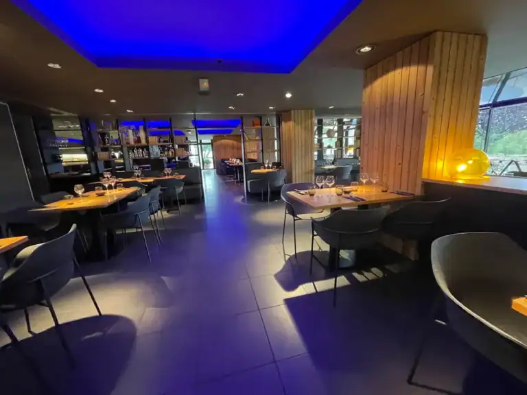 Salle intérieure du restaurant avec éclairage d'ambiance bleu et mobilier contemporain.