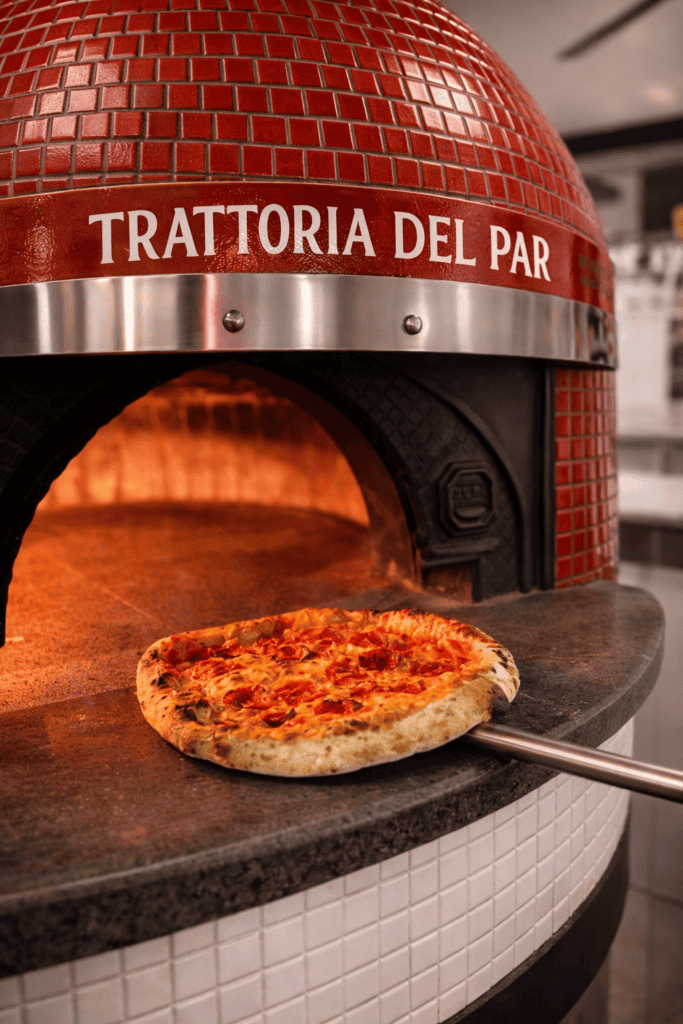 Pizza cuite au feu de bois devant le four napolitain de la Trattoria del Par à Chaudes-Aigues