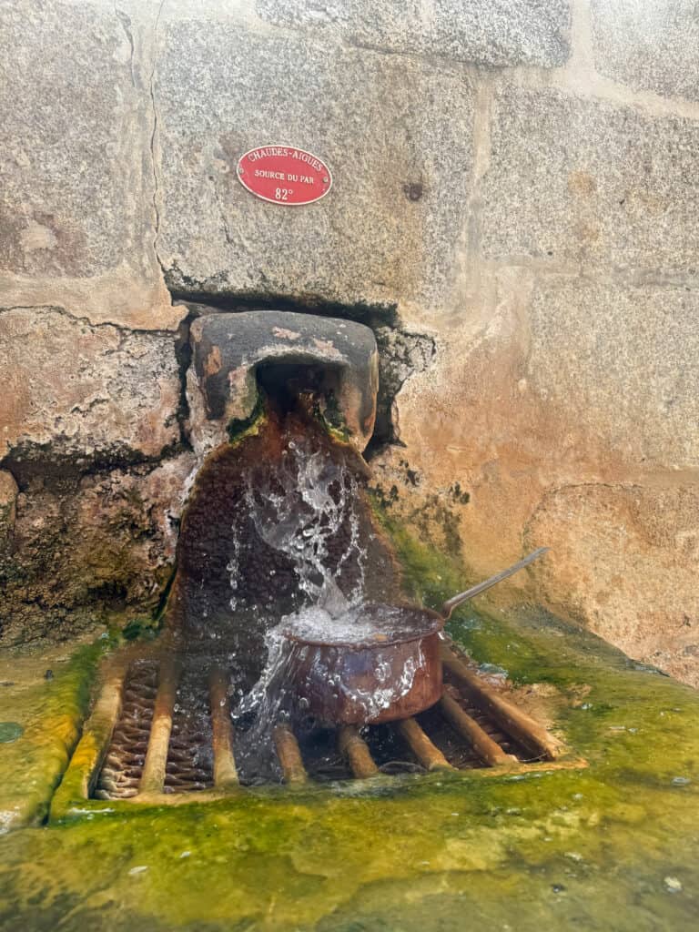 Casserole placée sous l'eau chaude de la Source du Par à Chaudes-Aigues pour la cuisson des œufs grâce à l'eau thermale.